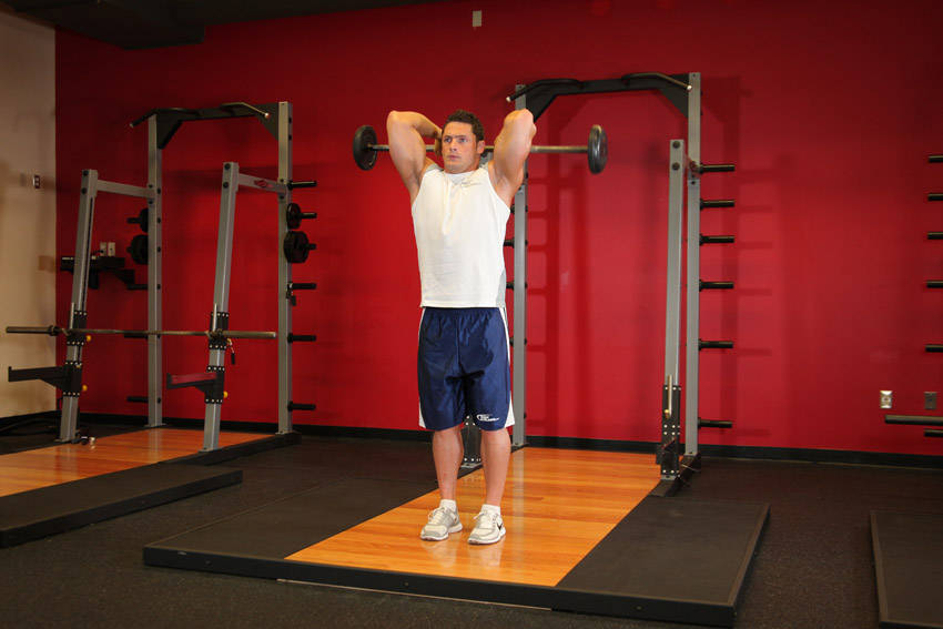 Demonstration of Standing Overhead Barbell Triceps Extension exercise showing proper form and technique
