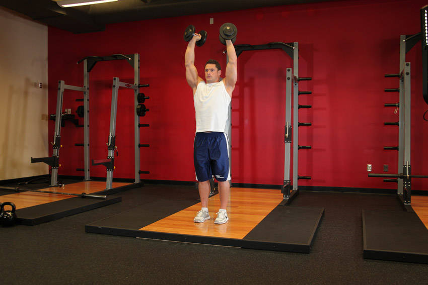 Demonstration of Standing Palms-In Dumbbell Press exercise showing proper form and technique