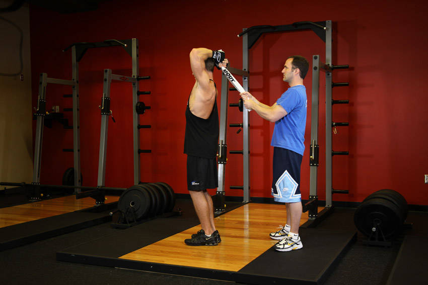 Demonstration of Standing Towel Triceps Extension exercise showing proper form and technique
