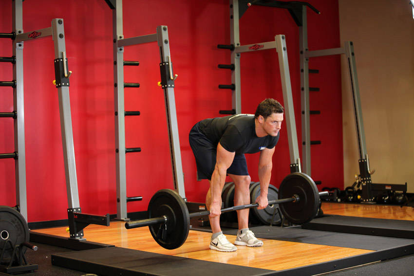 Demonstration of Stiff-Legged Barbell Deadlift exercise showing proper form and technique