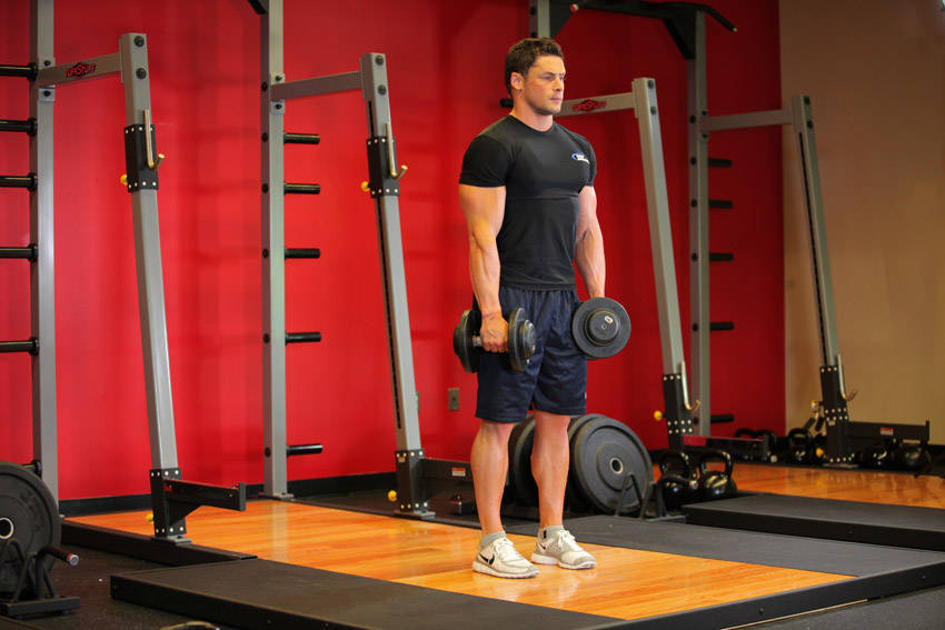 Demonstration of Stiff-Legged Dumbbell Deadlift exercise showing proper form and technique