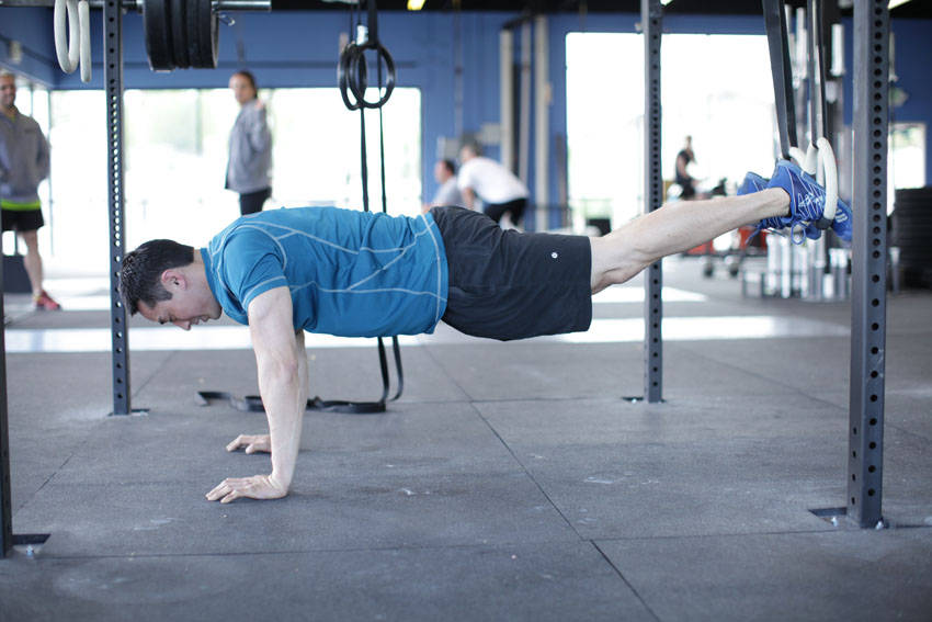 Demonstration of Suspended Reverse Crunch exercise showing proper form and technique