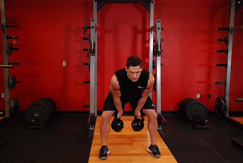 Demonstration of Two-Arm Kettlebell Clean exercise showing proper form and technique
