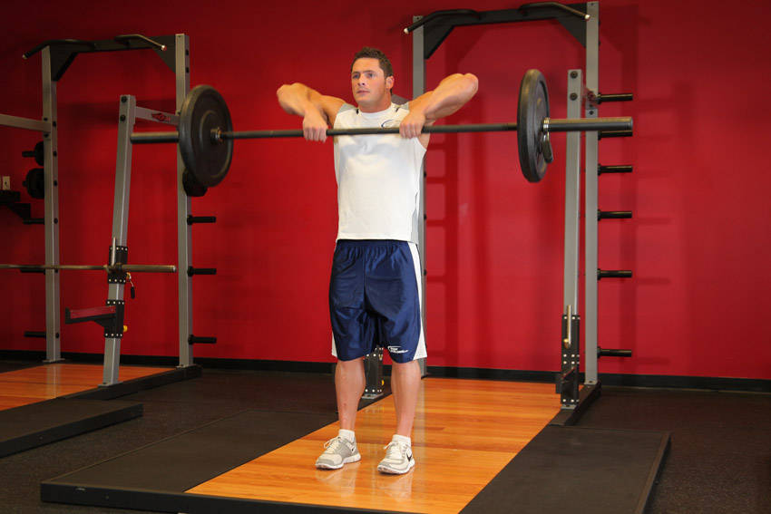 Demonstration of Upright Barbell Row exercise showing proper form and technique