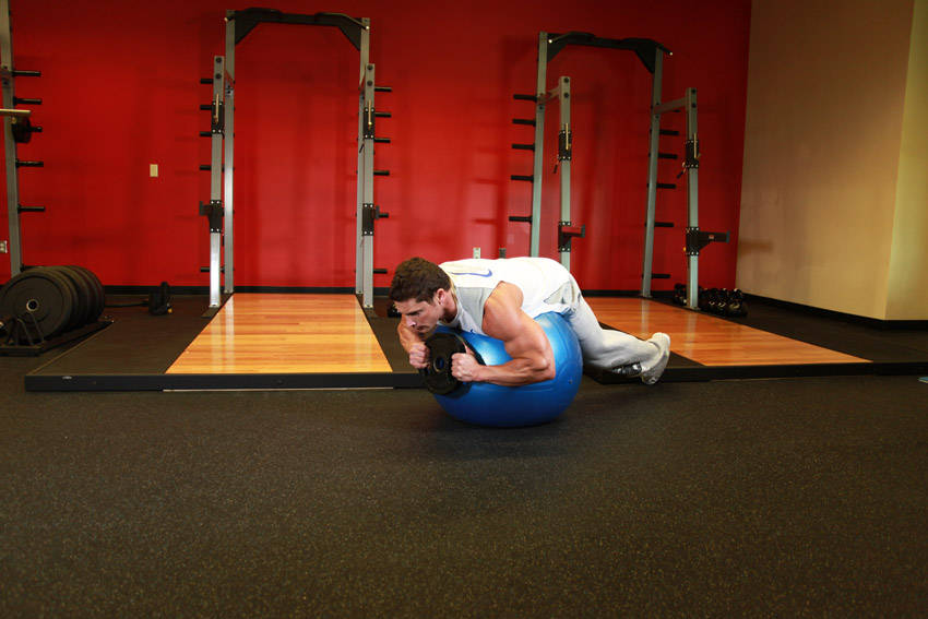 Demonstration of Weighted Ball Hyperextension exercise showing proper form and technique