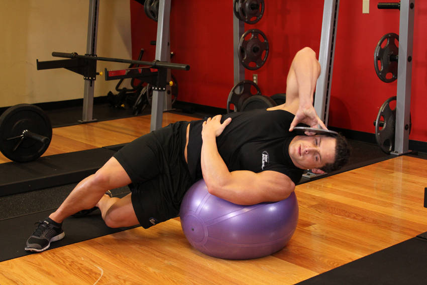Demonstration of Weighted Ball Side Bend exercise showing proper form and technique