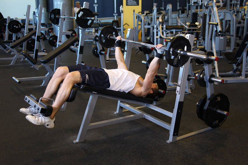 Demonstration of Wide-Grip Decline Barbell Bench Press exercise showing proper form and technique