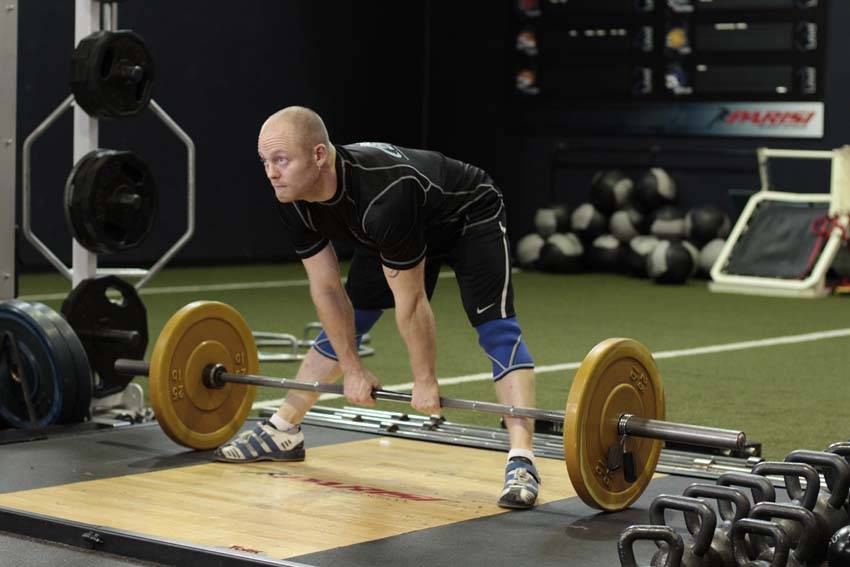 Demonstration of Wide Stance Stiff Legs exercise showing proper form and technique